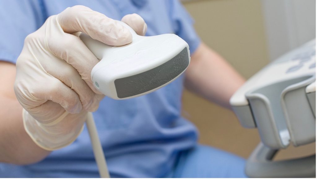 Képzett ultrahangos,  ultrahangos eszközzel vizsgálja a páciens heréit